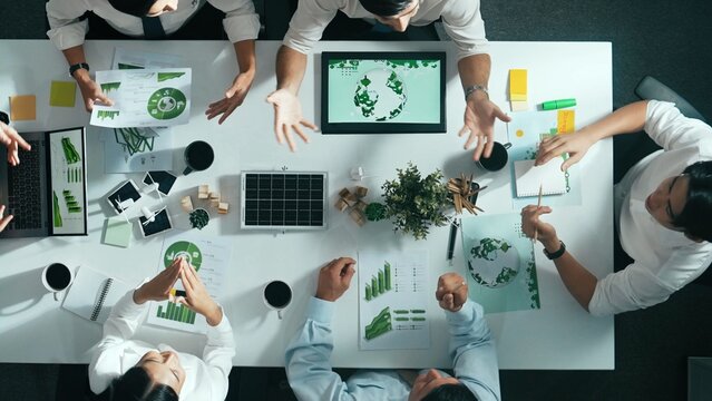Time lapse of business team discussing about using clean energy and sustainable investment at meeting table with wind mill, document with environmental graph and wooden house model. Alimentation.