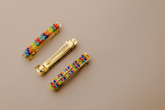 Vibrant colorful beaded barrettes with gold finish, accessory detail on a plain background, bright and playful hair fashion elements