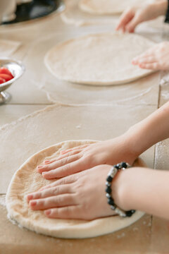 Chef hands preparing fresh pizza dough in kitchen before baking