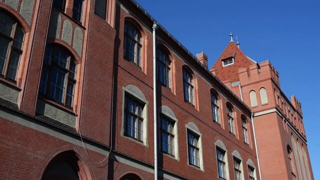 Large red brick building with a clock tower.   Torun is city on Vistula River in north-central Poland and UNESCO World Heritage Site.