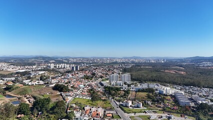 Fototapeta premium Imagem aérea de bairro em expansão com residências em construção, ruas organizadas e infraestrutura urbana em desenvolvimento, representando o crescimento imobiliário.