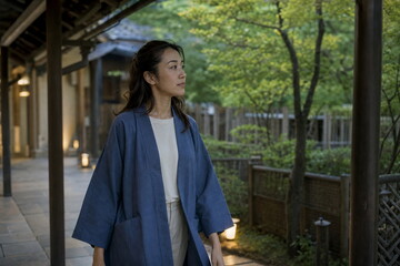 Fototapeta premium 緑の中庭に沿う木造回廊を歩く女性