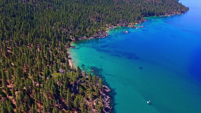 Aerial view captures emerald waters of Lake Tahoe with forest shadows tracing the shoreline
