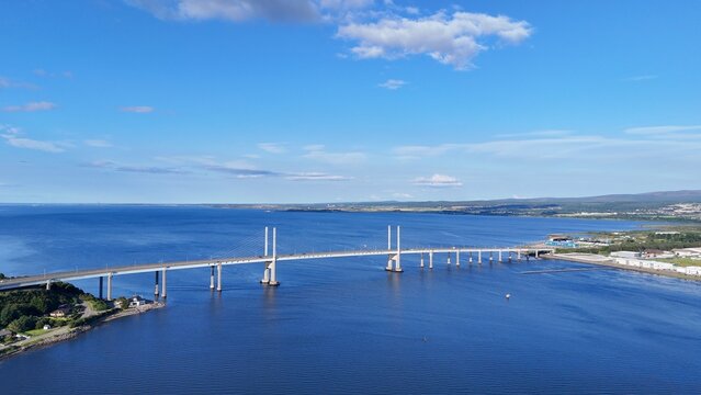 Inverness, Scotland, British coastal city enjoys clear daytime skies, overlooking the sea with a magnificent bridge amid stunning Highland landscapes.