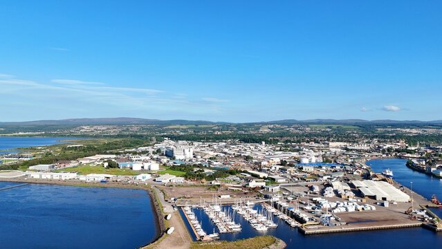 Far view of Inverness in Scotland, British landscape featuring the flowing river, coastal sea, green lands, hills, and cloudy daytime sky.