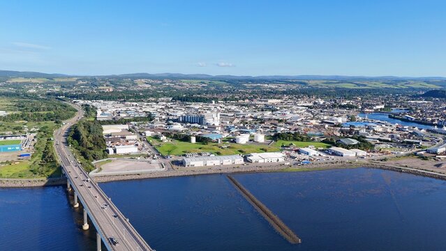 Inverness, Scotland, British city at daytime showcases a graceful bridge from the left, overlooking the sea beneath bright drifting clouds.