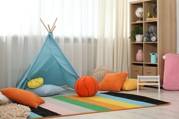 Blue wigwam, colorful pillows and shelving unit in stylish child's room. Interior design © New Africa