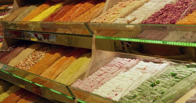 Rows of vibrant Turkish delight confections arranged on wooden shelves with green LED lighting in traditional spice market display.
