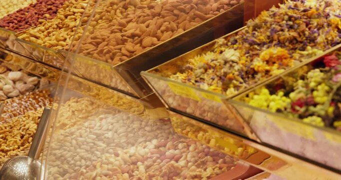 Vibrant assortment of dried botanicals, flowers, herbs in ornate golden display containers at traditional spice market or bazaar shop.