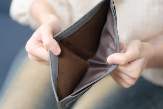 Financial hardship concept. Person showing an empty wallet at home, symbolizing money shortage, debt and personal budget stress. Empty wallet, finance, debt, poverty, budget.