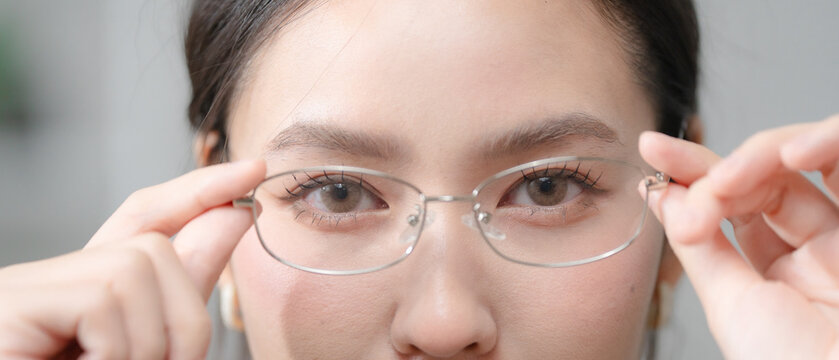Vision care concept. Close up of a young woman adjusting eyeglasses, representing clear vision, eye health and eyesight correction. Eyeglasses, vision, eyes, optical, healthcare.