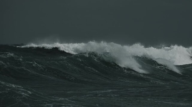 Black Ocean Waters Swaying and Rolling toward Beach. Dark Sky and White Crest Waves