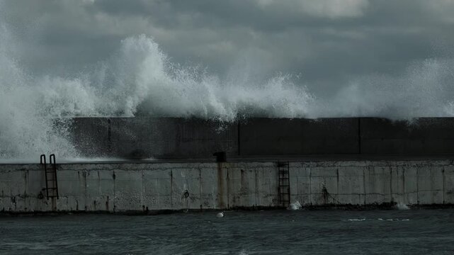 Rising Sea Waves Splashing Froth over Concrete Quay Walls