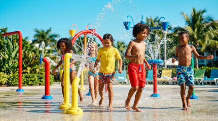 Obraz premium Diverse group of children running and playing in a sunny outdoor splash pad