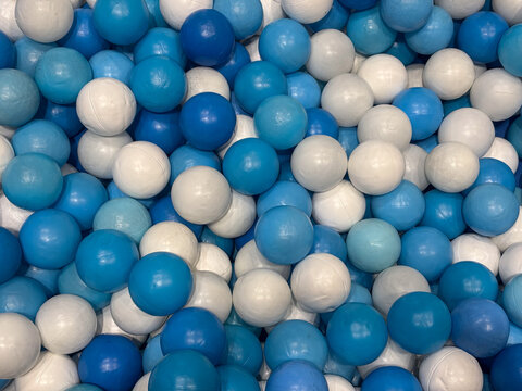 Blue and white plastic balls fill an indoor children's play area, creating an abstract and playful background suitable for recreation concepts.
