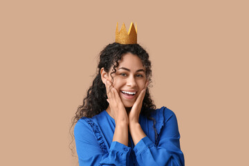 Happy young African-American woman in paper crown on brown background © Pixel-Shot