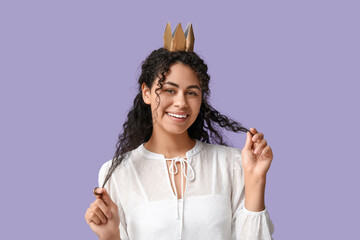 Beautiful young African-American woman in paper crown on lilac background © Pixel-Shot