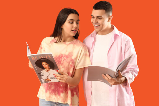 Young couple with magazines on orange background
