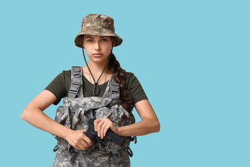 Fototapeta premium Confident young female soldier reloading handgun on blue background