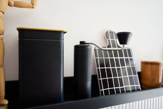 Coffee grinder and coffee accessories are arranged on kitchen shelf in home coffee corner