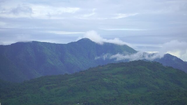 HAFLONG, ASSAM, INDIA - JANUARY 9: A beautiful cinematic time-lapse shot capturing white clouds moving fast and touching the lush green mountain peaks in Haflong. 4K footage.
