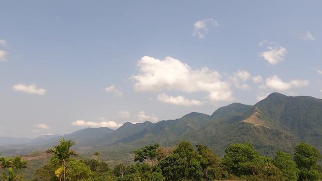 HAFLONG, ASSAM, INDIA - JANUARY 9: A beautiful landscape time-lapse shot capturing white clouds moving swiftly over the green mountain peaks under a clear blue sky on a bright sunny day in Haflong. 4K