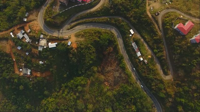 HAFLONG, ASSAM, INDIA - JANUARY 9: A spectacular aerial top-down drone view capturing a winding hillside road and residential houses nestled on the green slopes of Haflong hill station. 4K footage.