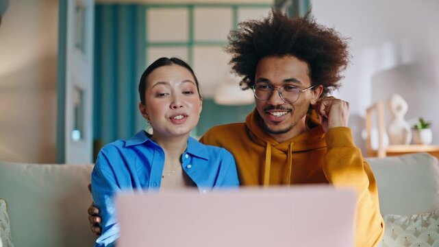 Couple video call laptop home sofa. Smiling pair waving greeting on online chat.