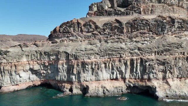 Pan shot along coastal cliff and Atlantic ocean in Puerto de Mogan on Canary Island Gran Canaria