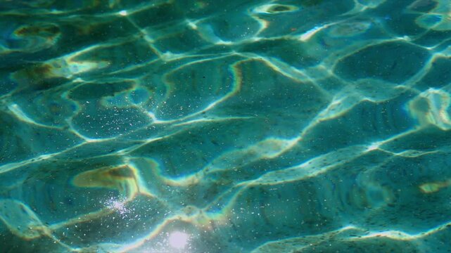 Close-up of murky pool water with ripple patterns and sunlight caustics, abstract aquatic surface detail, 4K