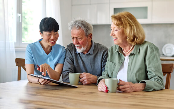Female caregiver with senior woman and man using laptop at home