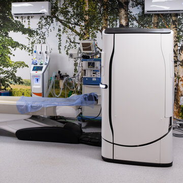 Modern medical room computed tomography equipped with specialized healthcare devices and patient bed.