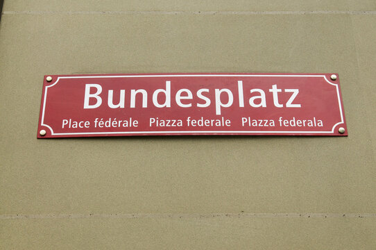 Multilingual Bundesplatz quarte street sign on a historic stone wall in Bern, Switzerland