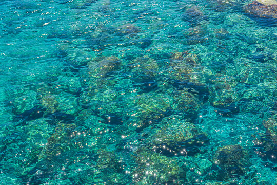 Glittering transparent ocean water surface reflecting bright summer sunshine in Greece