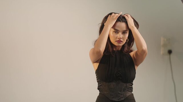 Intense close up of fashion model running both hands through her hair above her head in dramatic pose inside raw behind the scenes studio