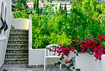 kącik wypoczynkowy na tarasie z czerwonymi kwiatami, białe krzesło na tarasie, Bugenwilla, Bougainvillea, sitting area in the garden, Recreation area © kateej