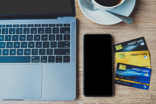 Credit card of laptop computer, smartphone empty screen and coffee cup on wooden background,Online banking Concept