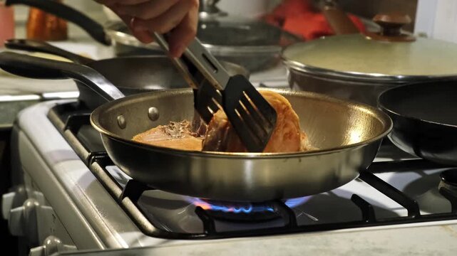 A neutral frying fish in a pan with spatula on a kitchen stove close-up silver and black stove top cooking tutorial food preparation natural light clean background. This scene is ideal.