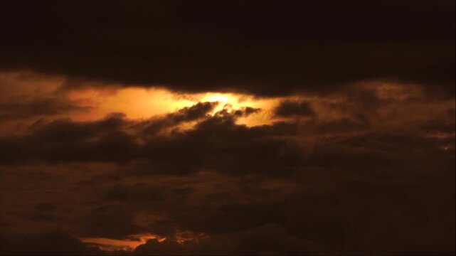 A dramatic cinematic time-lapse shot capturing thick, dense clouds gradually covering the glowing sun during sunset or sunrise over the hills of Haflong, Assam, India. 4K UHD