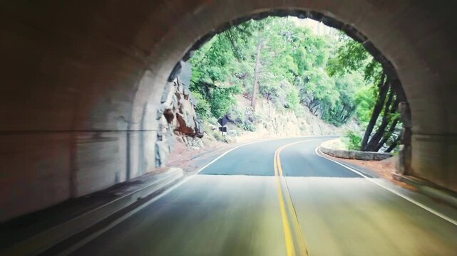 Scenic winding road curves through a tunnel with mountain views across Yosemite
