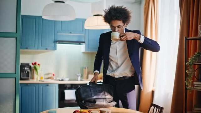 Businessman drinking coffee packing briefcase morning kitchen. Man leaving home