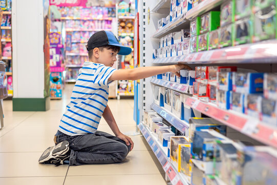 Little boy selecting toy in retail store, childhood shopping experience and consumer choice. Young child browsing toy store shelf