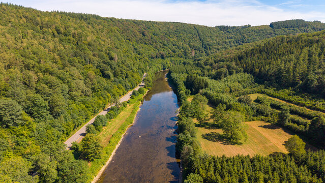 Drone photo of calm river flowing thought hills with forests