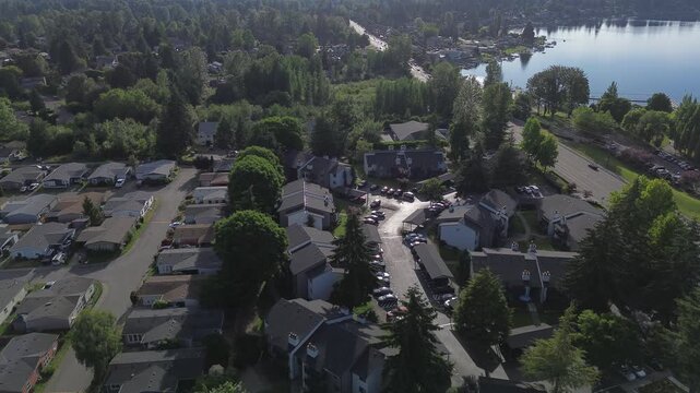 Tree lines shade streets, leading toward open lake vistas found in residential Kent, WA. Compact housing developments sit near water bodies, merging life with surroundings visible from flight