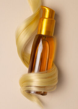 Hair Oil Bottle Wrapped in Blonde Hair Lock on Color Background, Hair Care Concept 