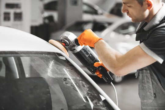 Worker polished white car with orbital polisher in auto repair shop, close-up. Vehicle detailing.