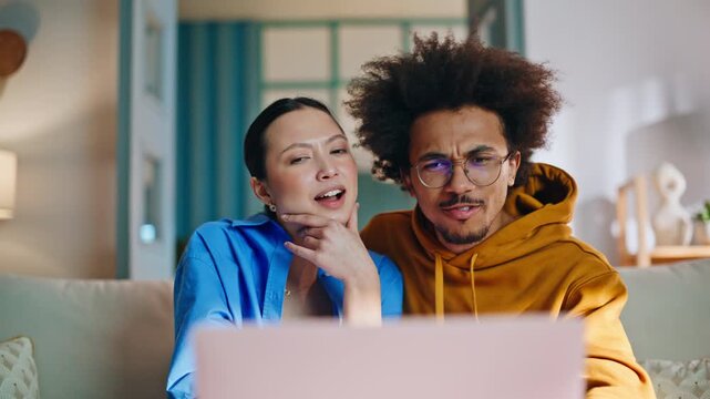 Multiethnic couple reacting laptop screen home sofa. Closeup surprised faces.