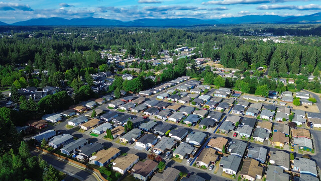 Residential dwellings follow uniform structured grid pattern nestled securely against thick forest buffers while consistent roofing designs highlight organized character of Kent community, WA