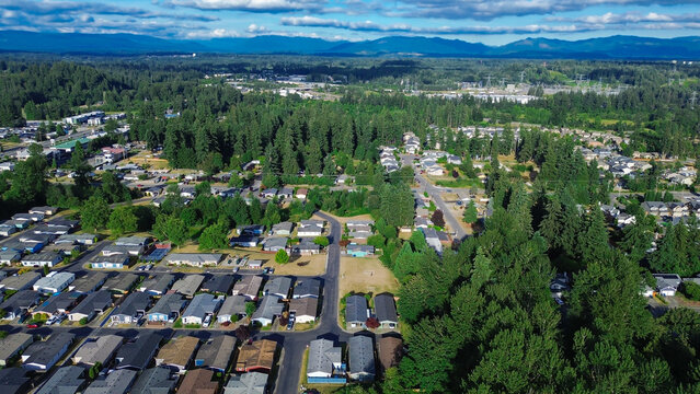 Aerial perspective reveals rapid suburban development extending toward northern evergreen horizon as residential clusters weave into dense timbered landscape near Kent city limits, Washington