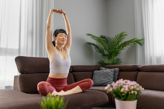 Japanese woman stretching in living room yoga pose for home wellness and mindfulness practice